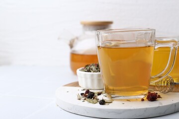 Delicious herbal tea with honey and dry leaves on white table, closeup. Space for text