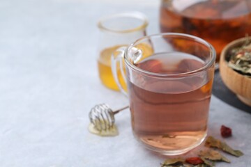 Delicious herbal tea with honey and dry leaves on grey table, closeup. Space for text