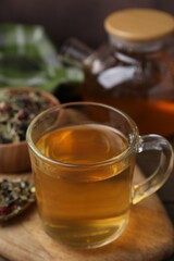 Delicious herbal tea and dry leaves on wooden table, closeup