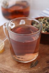 Delicious herbal tea, honey and dry leaves on white table, closeup