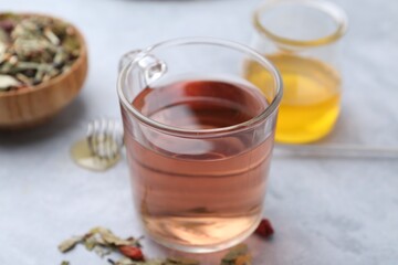 Delicious herbal tea and dry leaves on grey table, closeup