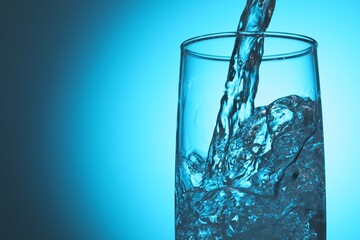 Pouring refreshing soda water into glass on light blue background, closeup. Space for text