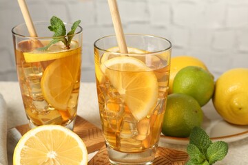Fototapeta premium Refreshing iced tea with drinking straws, mint, lemon and lime on light table against grey background, closeup