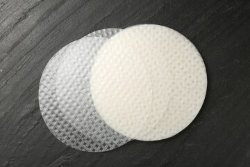 Edible rice paper sheets on dark textured table, flat lay
