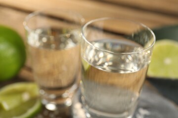 Tequila shots with limes on table, closeup