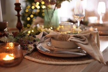 Christmas place setting with festive decor on wooden table in room, closeup