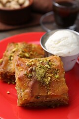 Tasty baklava with chopped nuts and scoop of ice cream on table, closeup