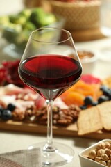 Red wine and different snacks served on table, closeup