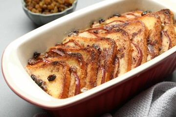 Delicious bread pudding in baking dish on light gray table, closeup