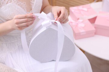 Bride opening beautiful wedding gift indoors, closeup. Space for text
