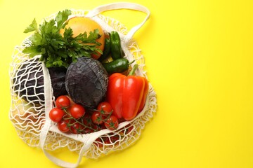 Eco bag with vegetables and grapefruit on yellow background, top view. Space for text