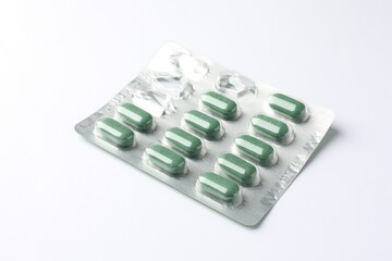 Blister with green pills on white background