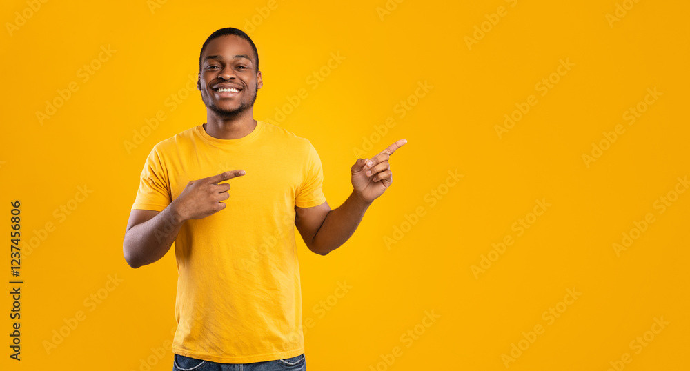 Aufkleber look there. cheerful african american man pointing fingers aside showing empty space for text posing