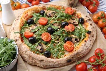 Tasty pizza with cherry tomatoes, black olives, mushrooms and arugula on table, closeup