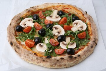 Tasty pizza with cherry tomatoes, black olives, mushrooms and arugula on white tiled table, closeup
