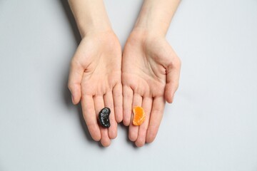 Woman with tangerine segments of different colors on light grey background, top view