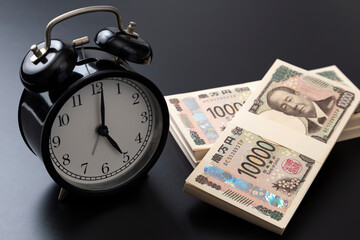 黒背景に時計と札束