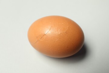 One egg with cracked shell on light grey background, closeup