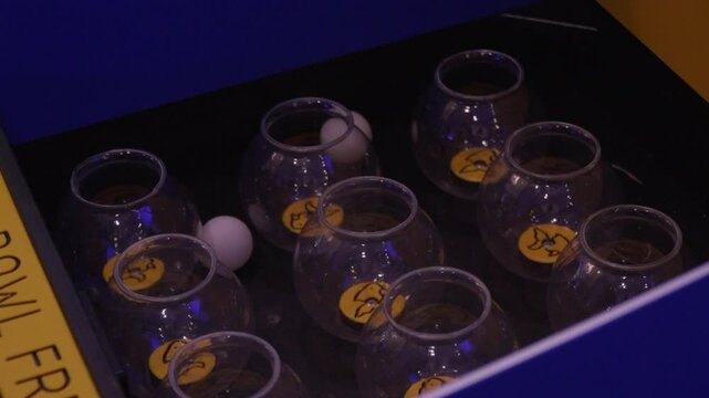 Ping pong balls thrown into glass fish bowls game, hands toss with chance and skill