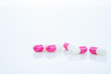 Pink-white antibiotic capsules spread on white background. Prescription drug. Antibiotic resistance in modern medicine. Healthcare and pharmaceutical industry. Medical care, pharmaceutical research.