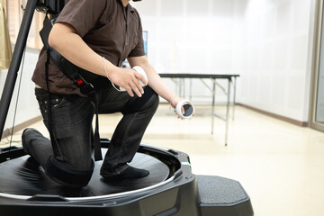 Person using a VR treadmill with controllers, engaging in a virtual reality experience for...