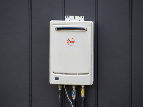 Rheem White Tankless Gas Water Heater Installed at Dark Exterior Wall