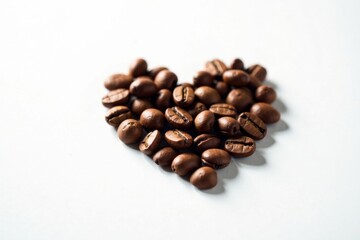 Naklejka premium Aromatic Roasted Coffee Beans Arranged in a Heart Shape on a Plain White Background