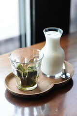 a glass of iced matcha cube and a pitcher of milk 