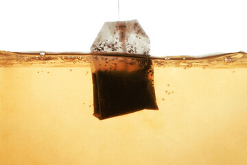 Putting tea bag into glass cup on white background, closeup