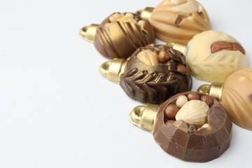 Delicious chocolate in shape of Christmas baubles on white background, closeup. Space for text