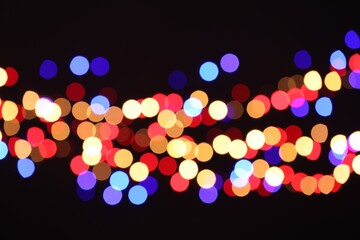 Blurred view of colorful lights on black background, bokeh effect
