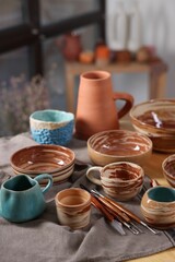 Different beautiful pottery and set of clay crafting tools on table indoors