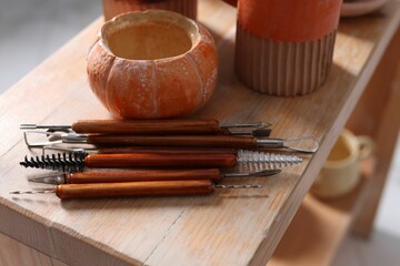 Set of different crafting tools and pottery on wooden shelf indoors, closeup