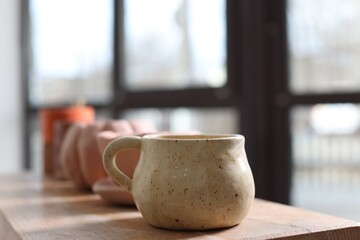 Beautiful pottery on wooden shelf indoors, closeup