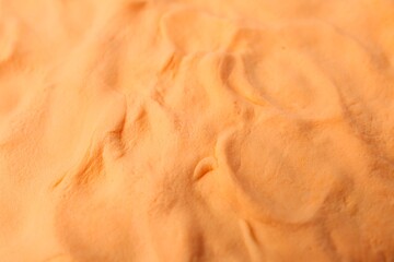Bright orange play dough as background, closeup