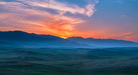 Silhouetted Green rolling hills at dusk. Pink, red, orange sunset over California wilderness
