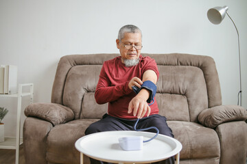 Portrait Of Senior Man Measuring Blood Pressure Using Electronic Medical Device At Home 