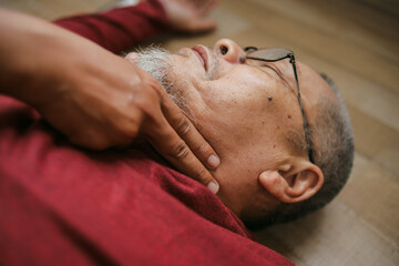 Close-up Hand Checking Pulse Of Unconscious Senior Man At Home  