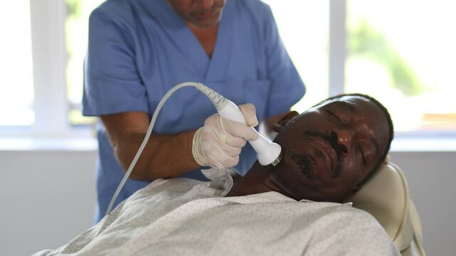 Adult African American undergoing high frequency ultrasound therapy to reduce fine wrinkles and rejuvenate facial skin by stimulating collagen production. Modern cosmetology and male grooming concept