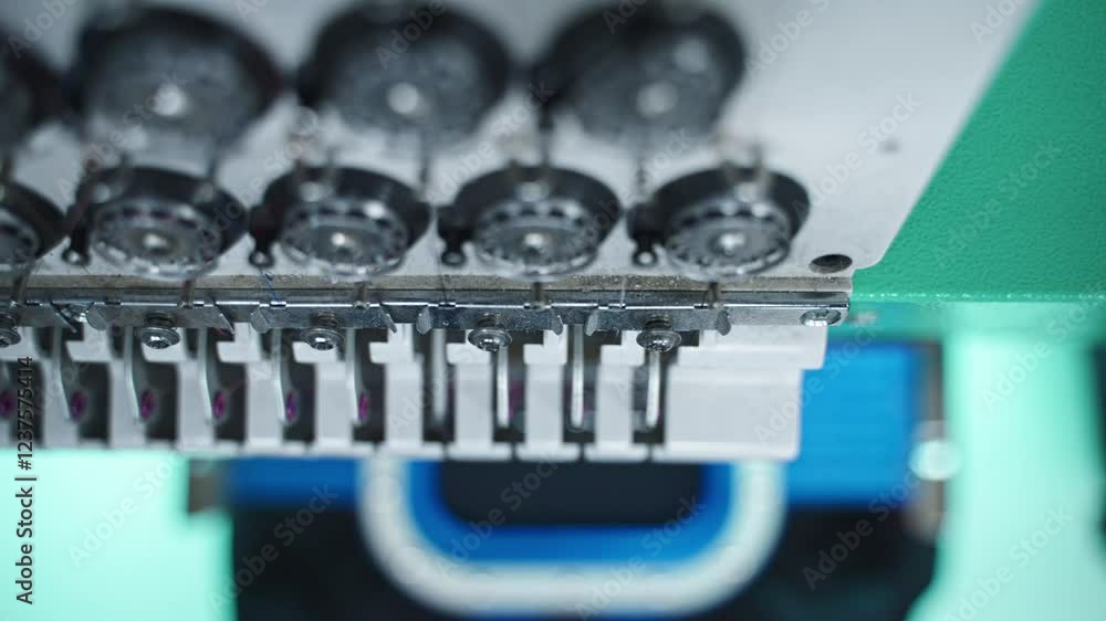 Poster spools of thread in an embroidery machine ready for stitching, high overview of bobbin spinning and 