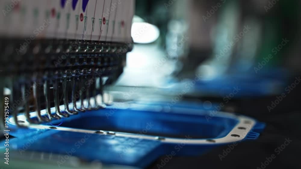 Poster needles and threads in motion during embroidery production closeup as hoops shift and adjust to diff