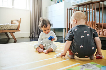 Fototapeta premium Babies playing, game and kid toys for mobility development and learning together in a home bedroom. Nursery, toy brick and cute children with block play thing and activity in a house on the floor