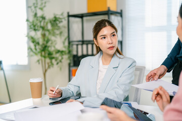 A professional woman engaged in a meeting, attentively listening while holding a pen and surrounded...