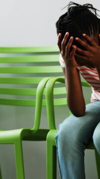 Upset girl sitting on chair in hospital corridor