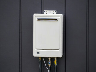 White Tankless Gas Water Heater Installed at Dark Vertical Panel Wall