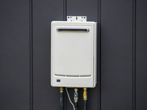 White Tankless Gas Water Heater Installed at Dark Vertical Panel Wall