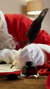 Santa Claus sleeping at desk while writing a letter with a quill