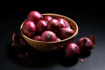 Fresh red onions in a bamboo basket on black background. Harvest concepts. Organic vegetables.