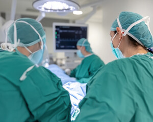 Healthcare professionals in surgical attire focus on patient during procedure, showcasing teamwork and dedication in sterile environment