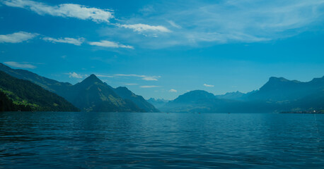 Alps mountain background. Swiss Alps mountain on sunny day. Mountain under clouds in blue sky. Blue nature background. Blue lake with blue sky near mountain.